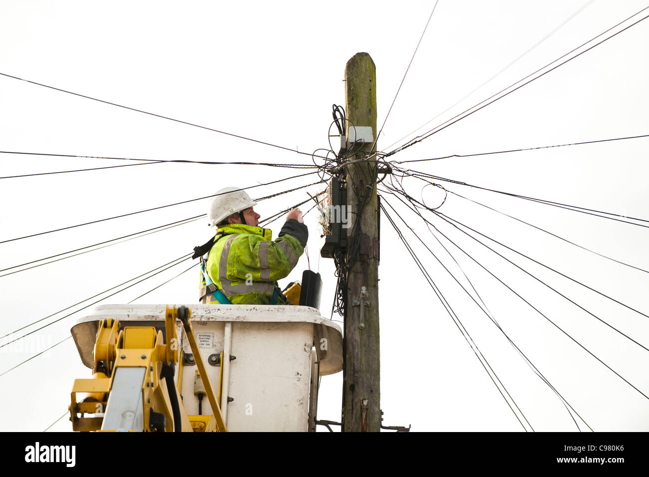 Un BT British Telecom engineer la riparazione di una linea telefonica da una piattaforma sopraelevata, REGNO UNITO Foto Stock