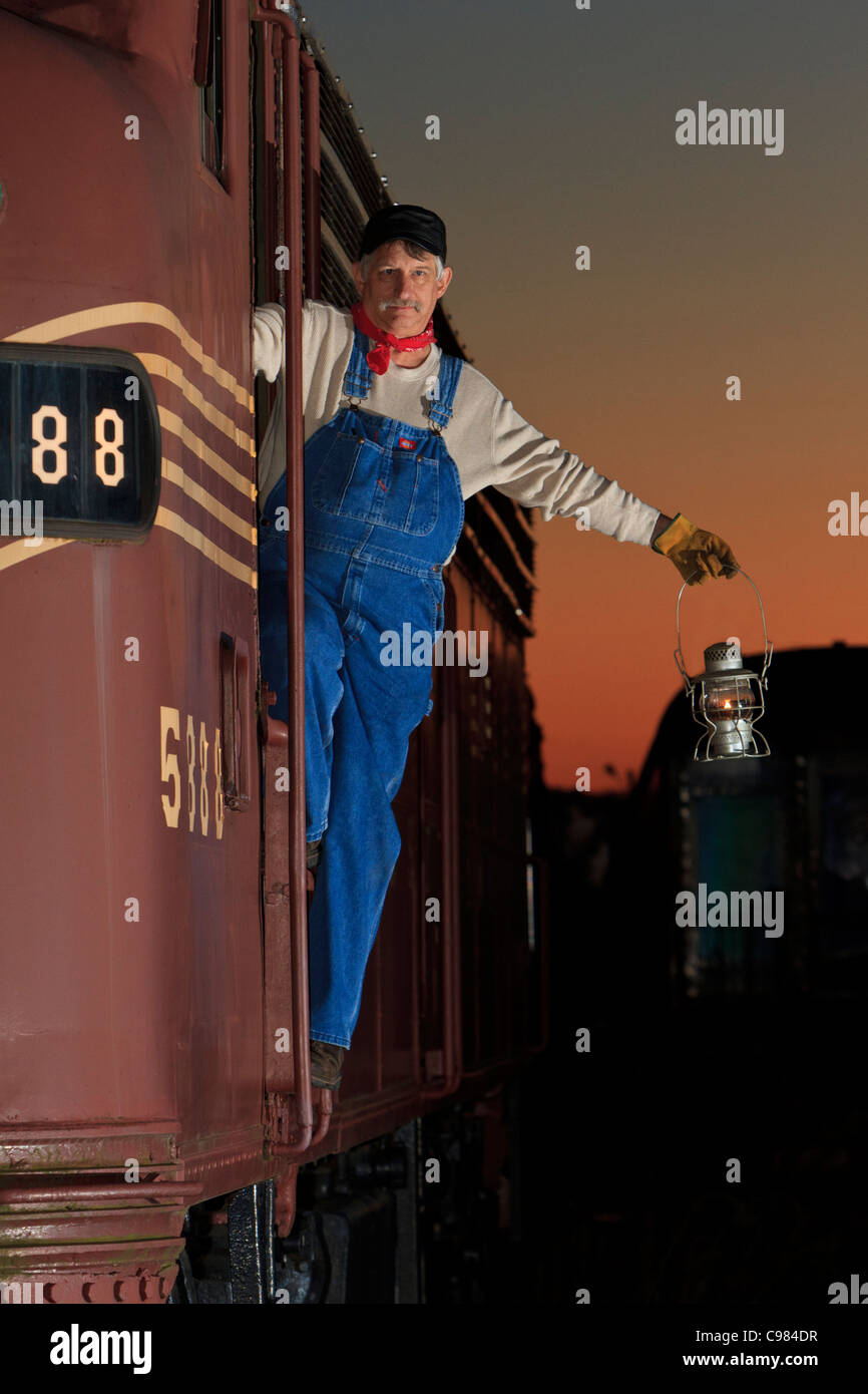 Uomo in posa come treno ingegnere con la lanterna e locomotori Foto Stock