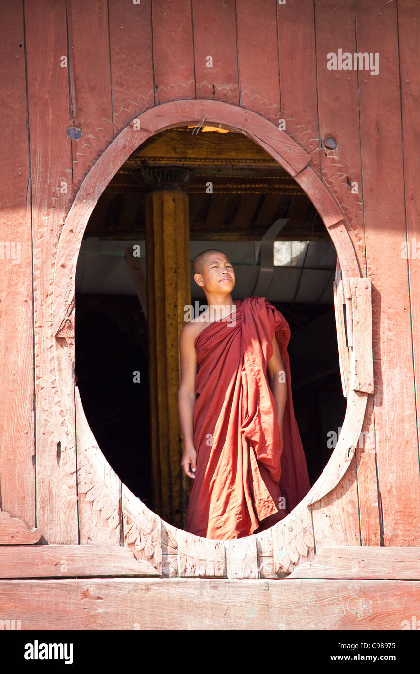 Giovani monaci sta guardando dal monastero finestra ovale in Shwe Yaunghwe monastero a Nyaungshwe, stato Shan del Myanmar Foto Stock