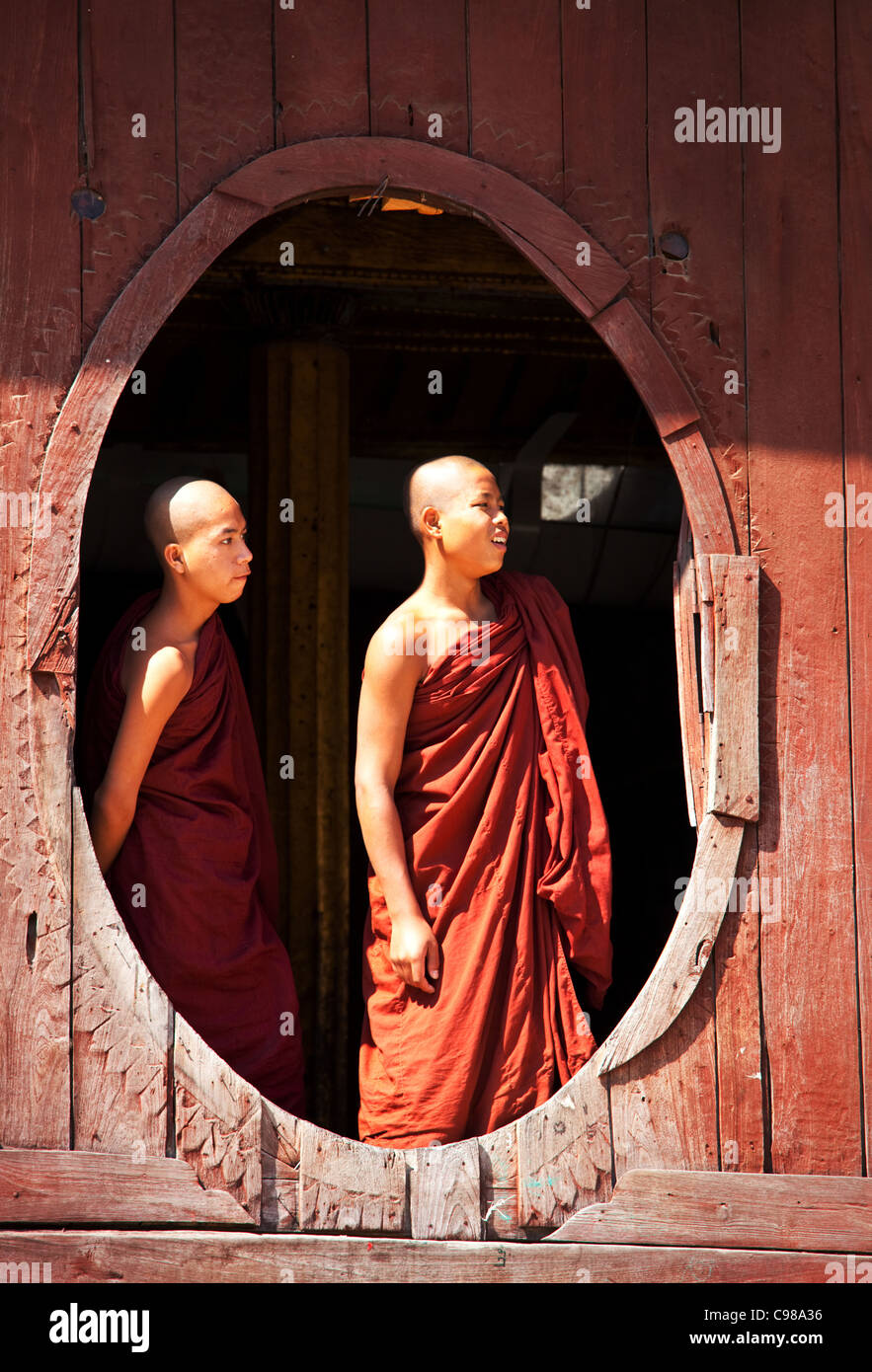 Giovani monaci sta guardando dal monastero finestra ovale in Shwe Yaunghwe monastero a Nyaungshwe, stato Shan del Myanmar Foto Stock