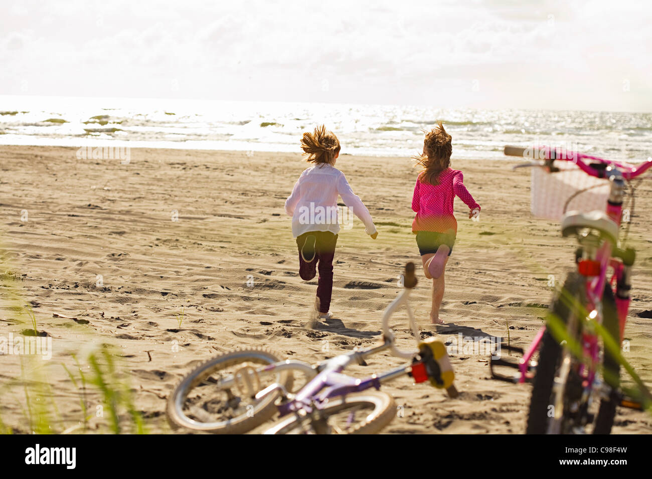 Le ragazze a correre verso la spiaggia del mare Foto Stock