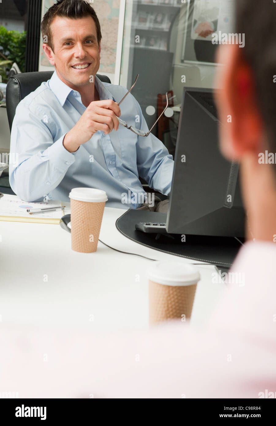 Due colleghi di sesso maschile seduto dietro le loro scrivanie Foto Stock