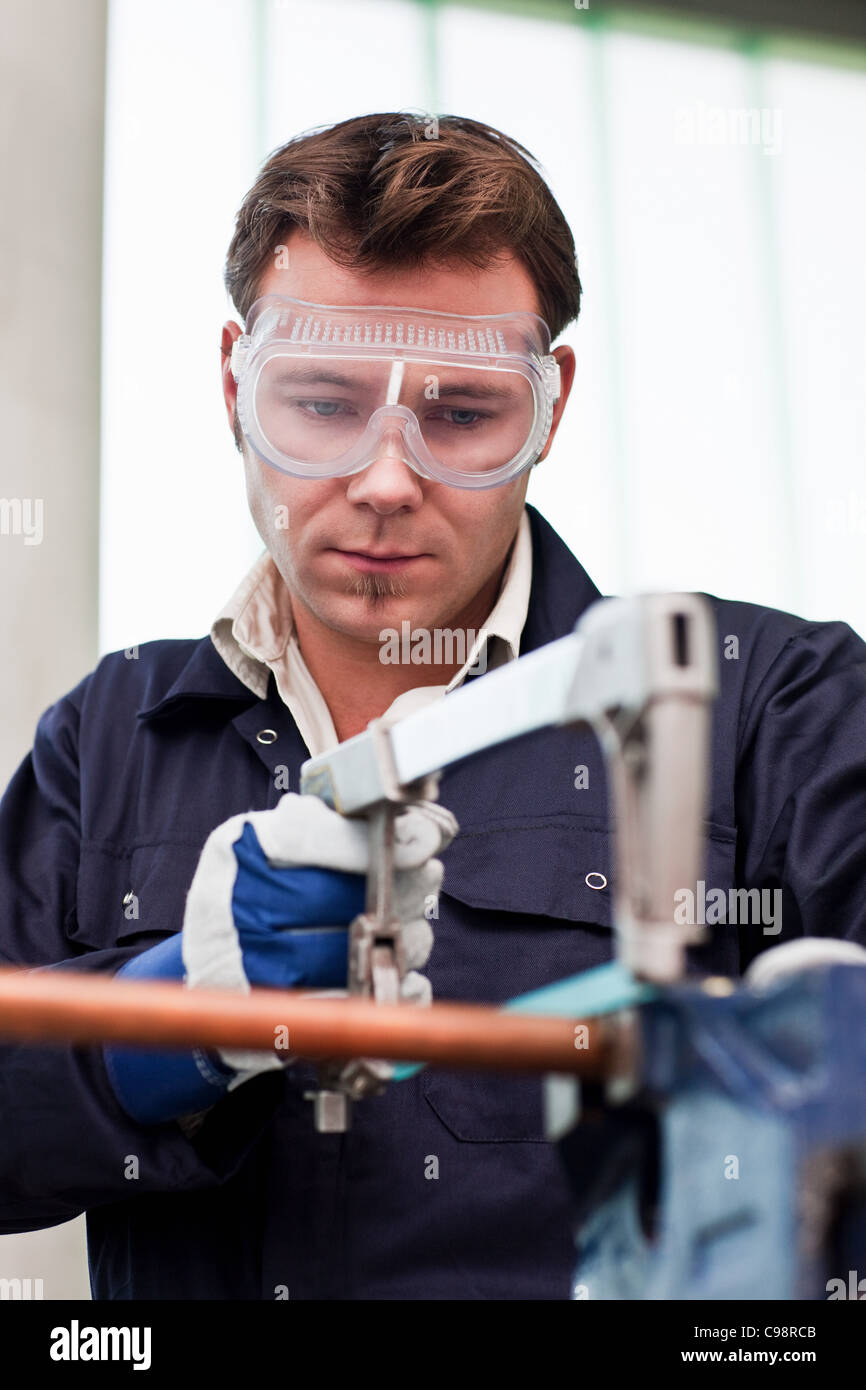 Plumber taglio in tubo di rame in officina Foto Stock