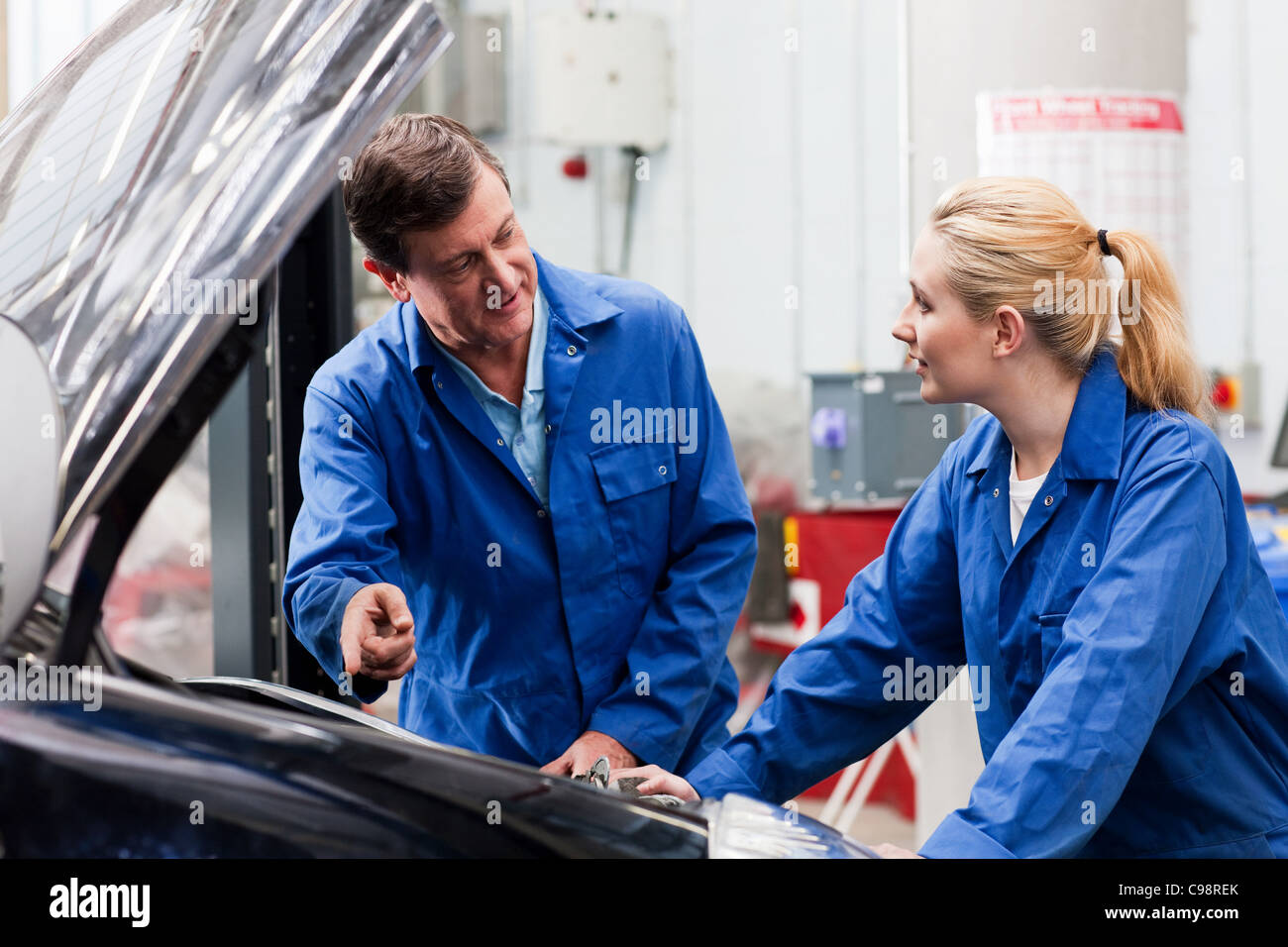 Mechanic disussing auto a motore con apprendista Foto Stock