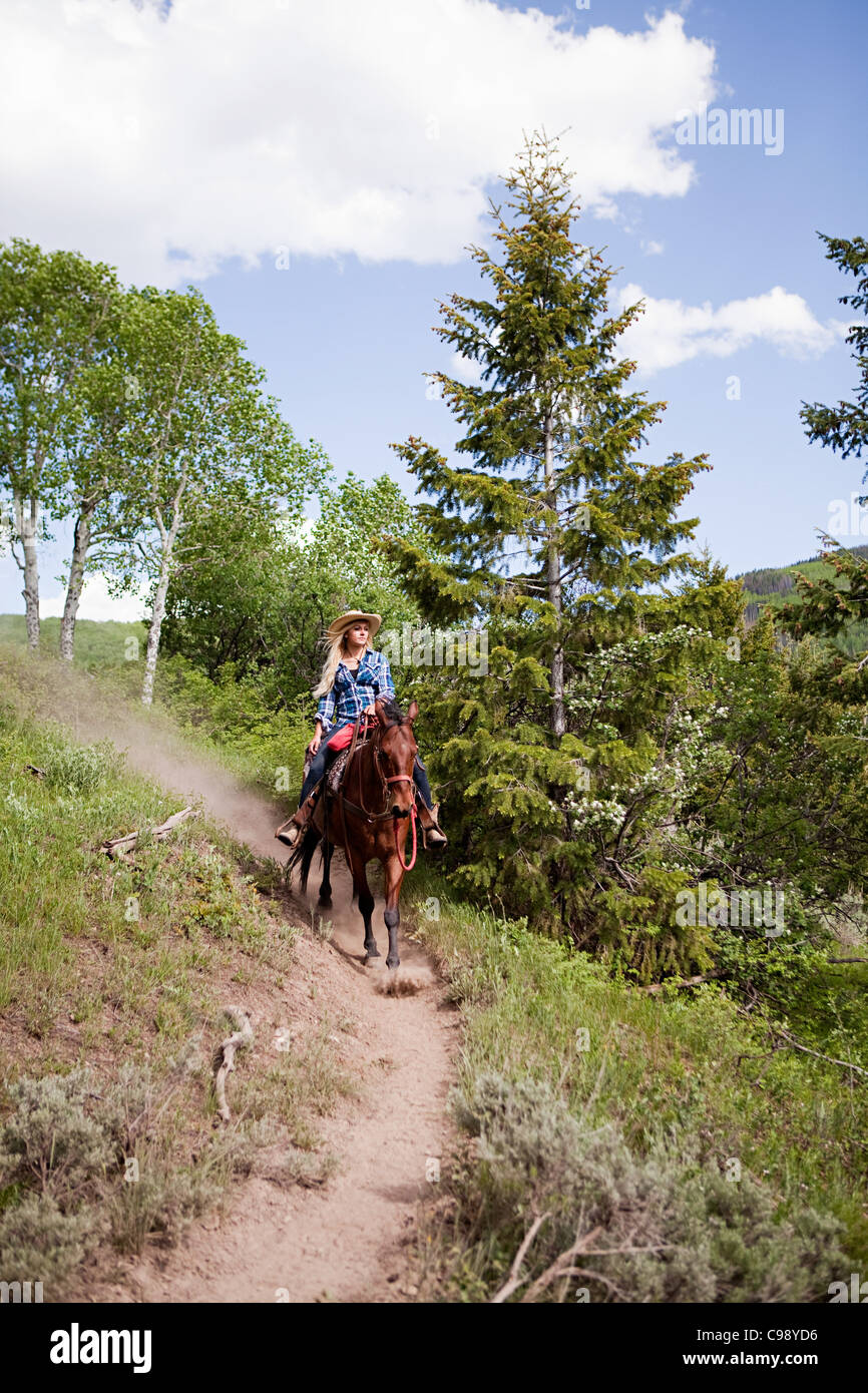 La donna a cavallo attraverso Beaver Creek, Colorado, STATI UNITI D'AMERICA Foto Stock