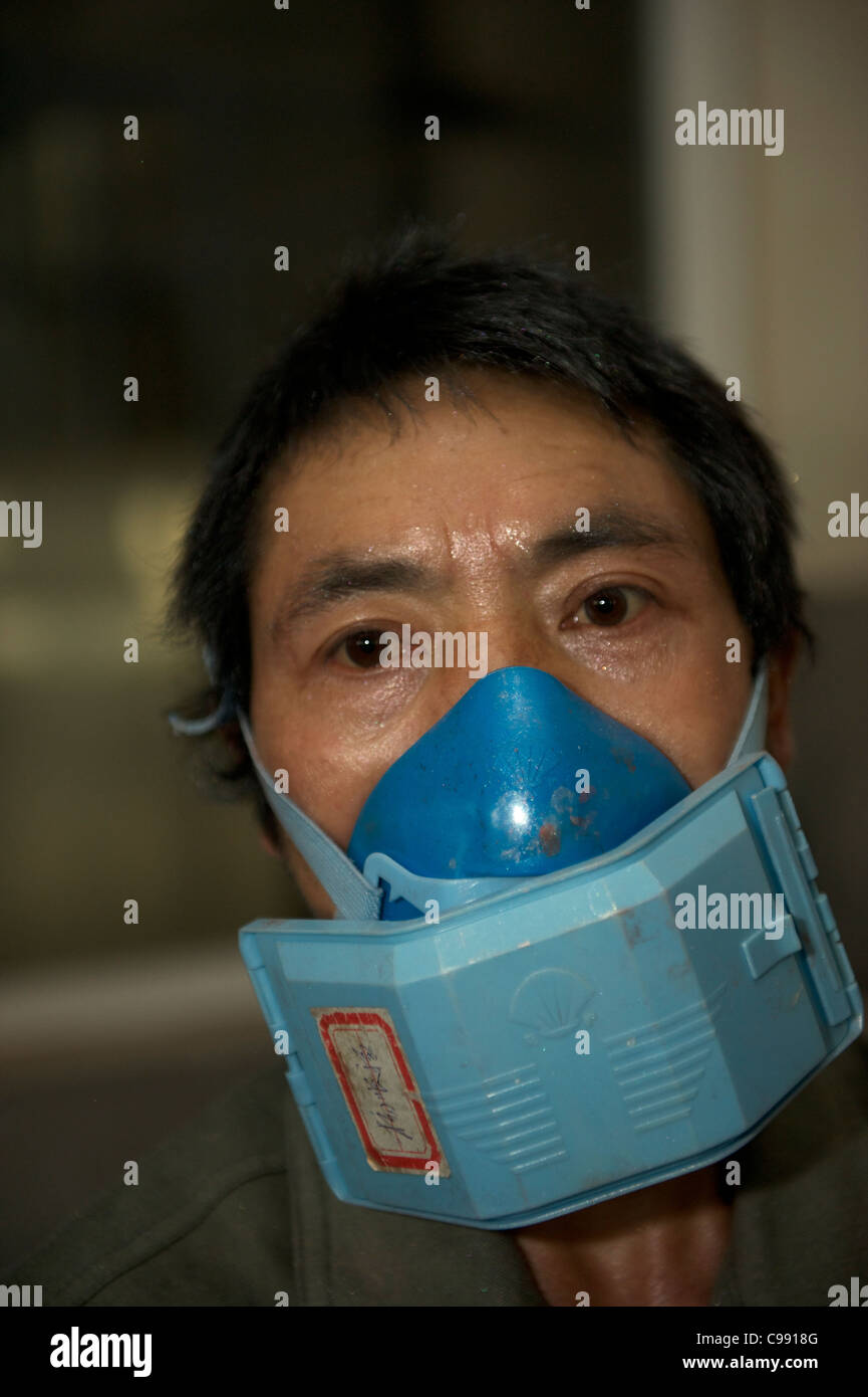 Un lavoratore cinese con una maschera che lavora in una polvere fluorescente fabbrica in Ninghai, Zhejiang, Cina. 11-Nov-2011 Foto Stock