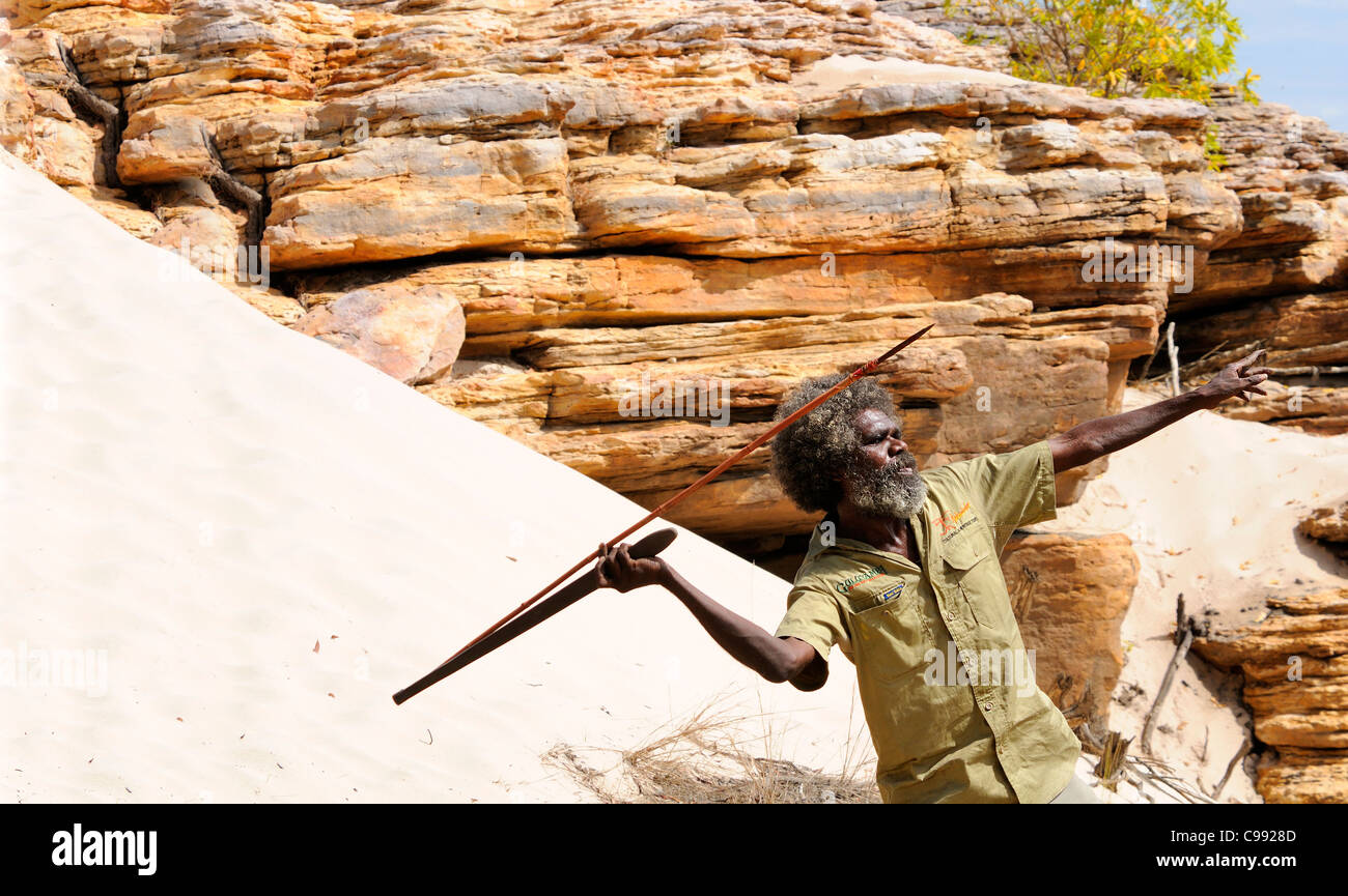 Uomo aborigeno dimostrando lancia gettando contro il fondale di rocce dorate di Arnhem Land,estremità superiore, il Territorio del Nord, l'Australia Foto Stock