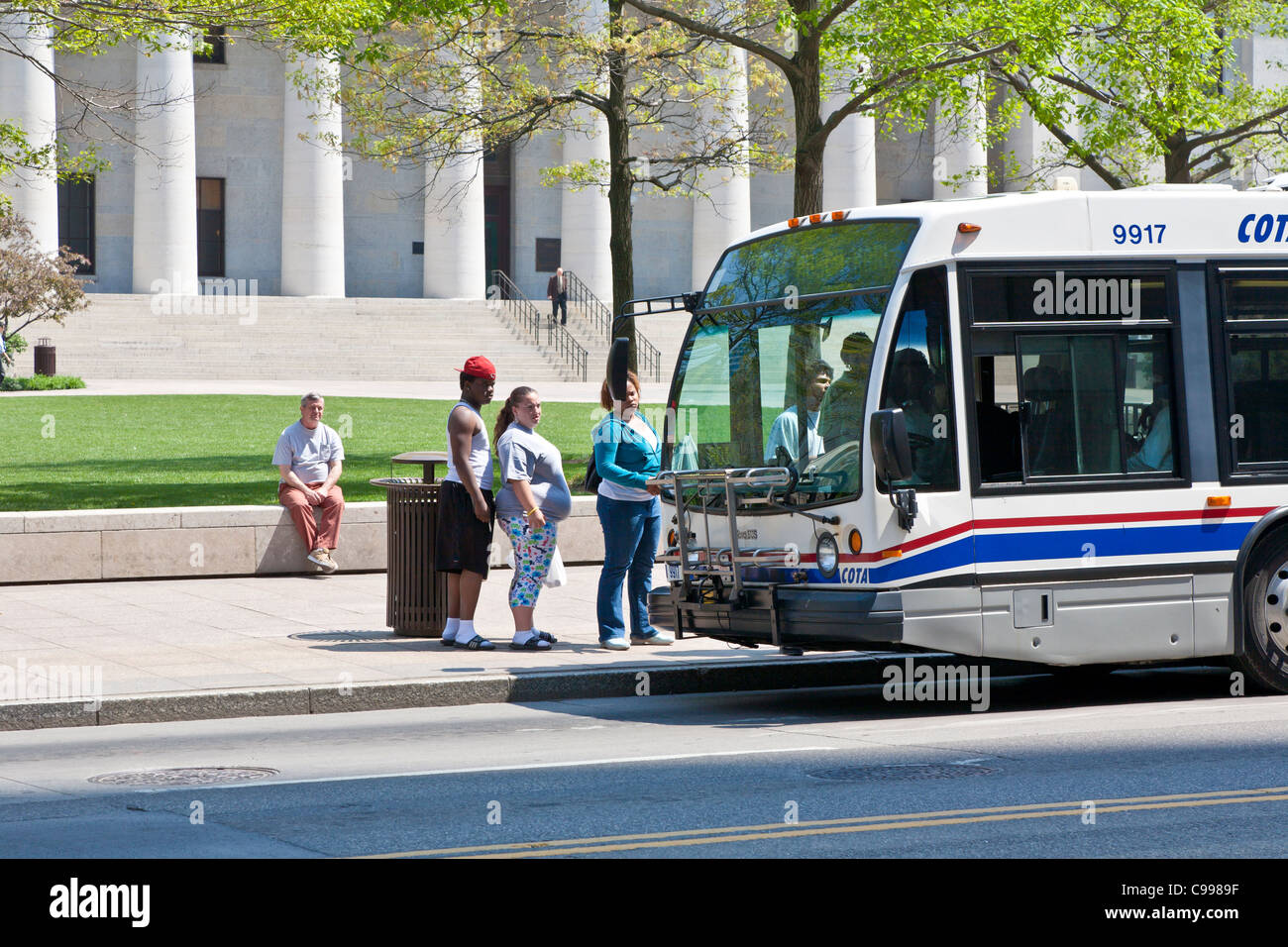 Donna obesa in attesa in fila per entrare in autobus pubblico di fronte all'Statehouse nel centro di Columbus, Ohio. Foto Stock