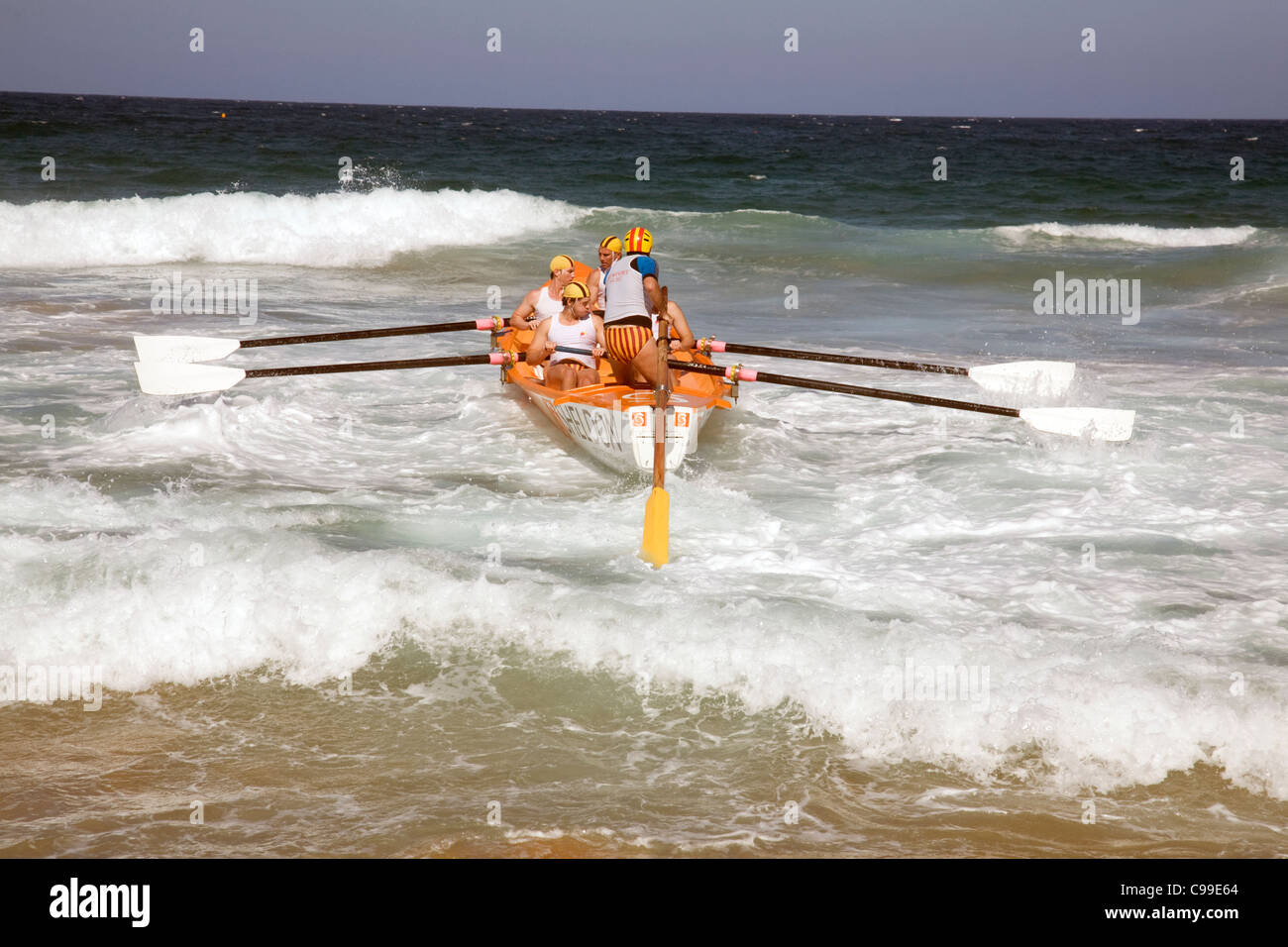 Equipaggio di una tradizionale barca australiana di salvataggio surf canottaggio in una corsa al largo di Newport Beach, Sydney, Australia Foto Stock