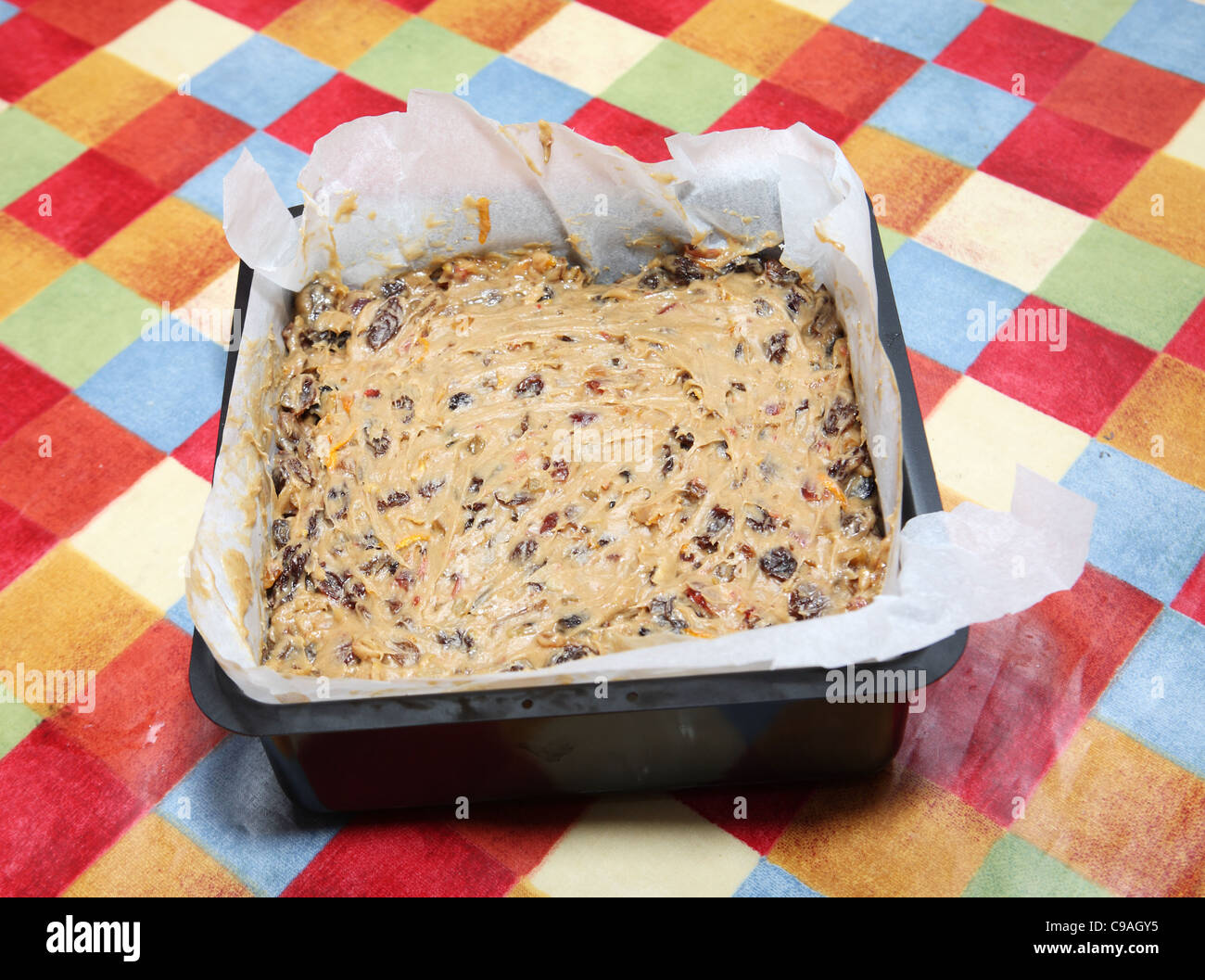 La realizzazione di una torta di Natale, la torta pronta per la cottura in un quadrato di cottura rivestito di stagno con carta oleata Foto Stock