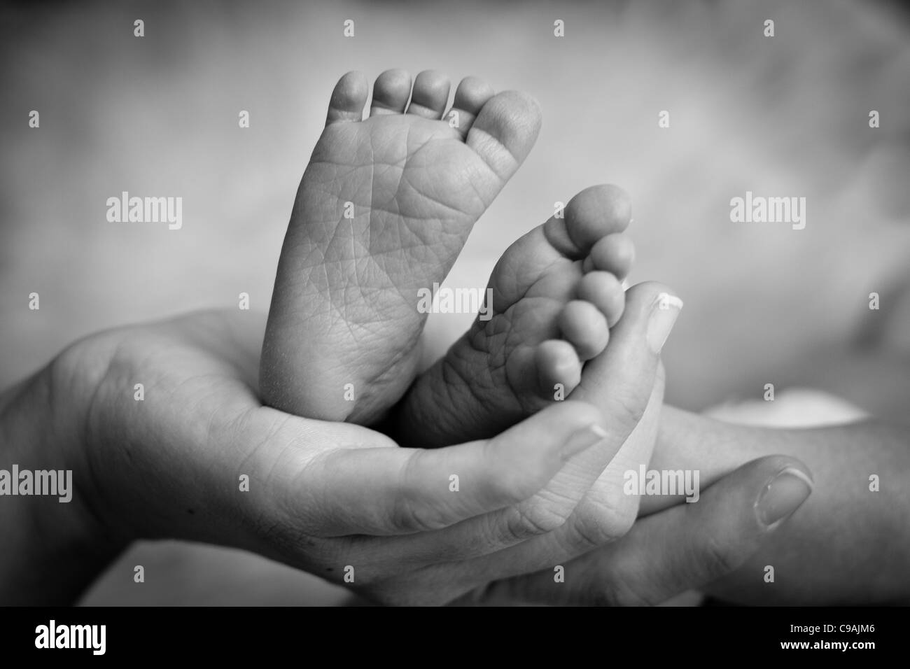 Madre che tiene delicatamente le gambe del bambino Foto Stock