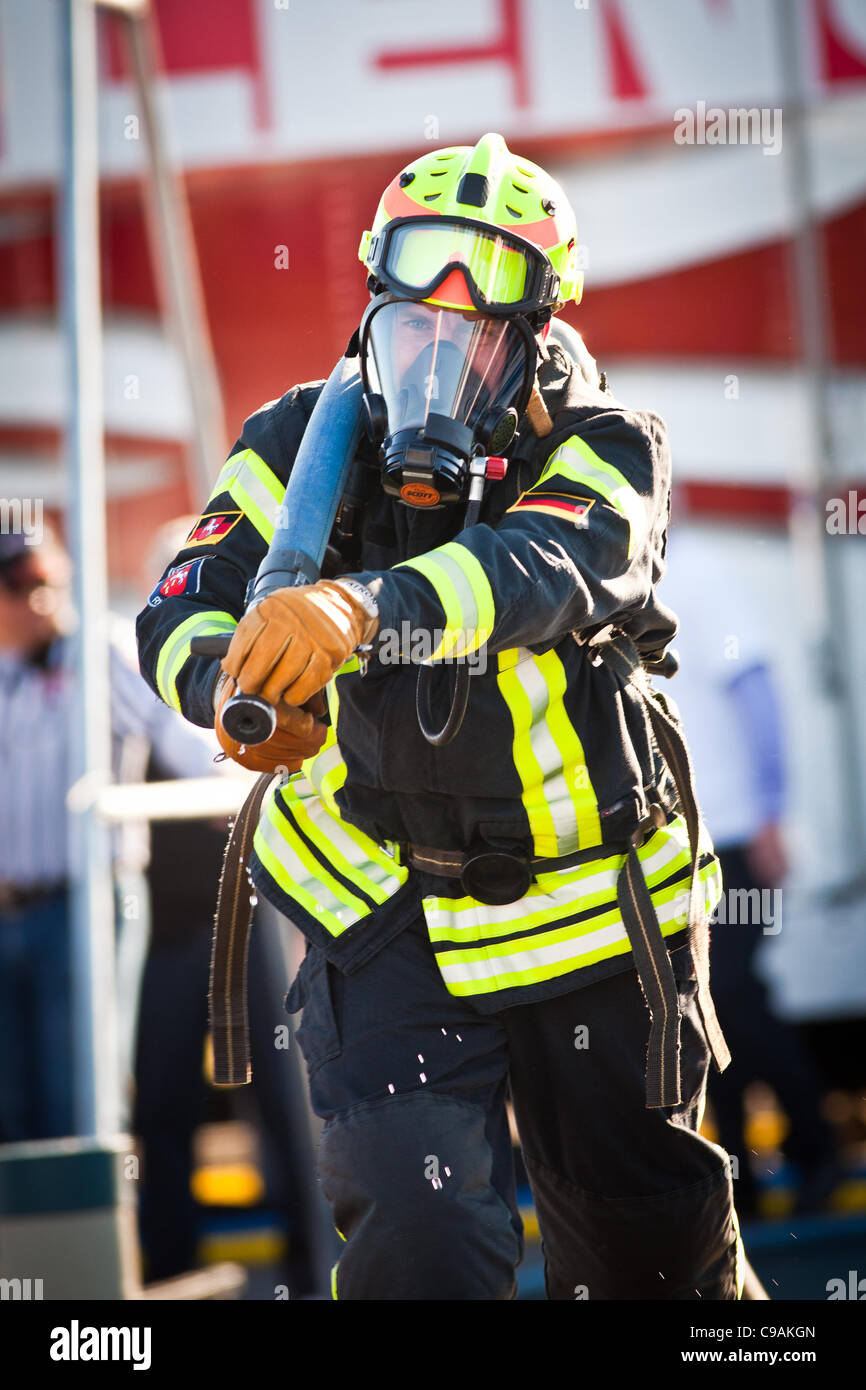 Un vigile del fuoco gare con un modello Firehose mentre indossa l'estinzione completa ingranaggio e lavorano contro l'orologio durante le finali internazionali del pompiere combattimento Challenge il 18 novembre 2011 in Myrtle Beach, Carolina del Sud. Foto Stock