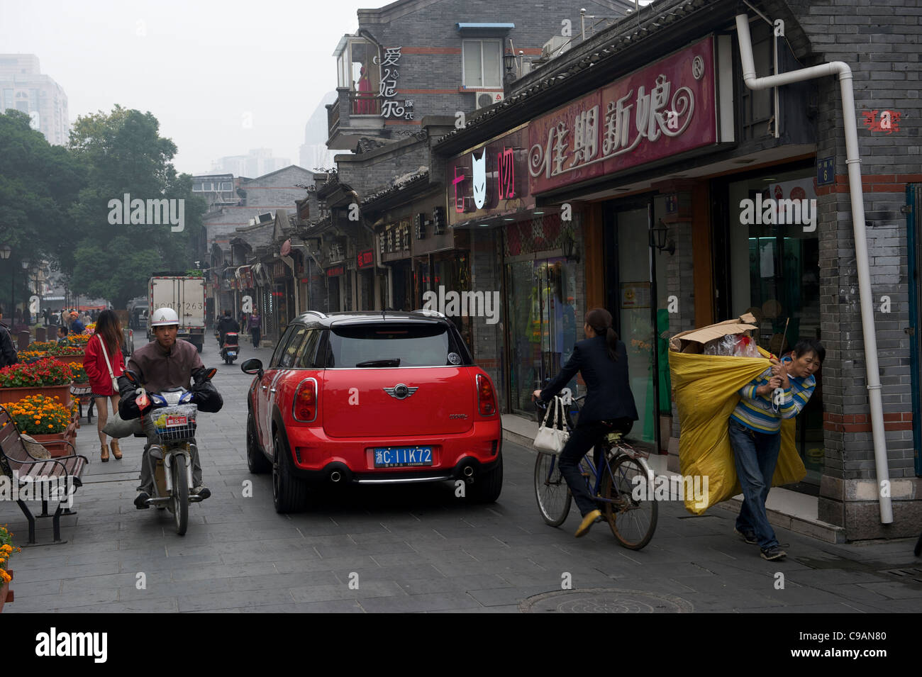 Una mini cooper trascina lungo una bicicletta, un'autovettura elettrica e un anziana signora che trasportano la spazzatura in Wenzhou, Zhejiang, Cina. 2011 Foto Stock