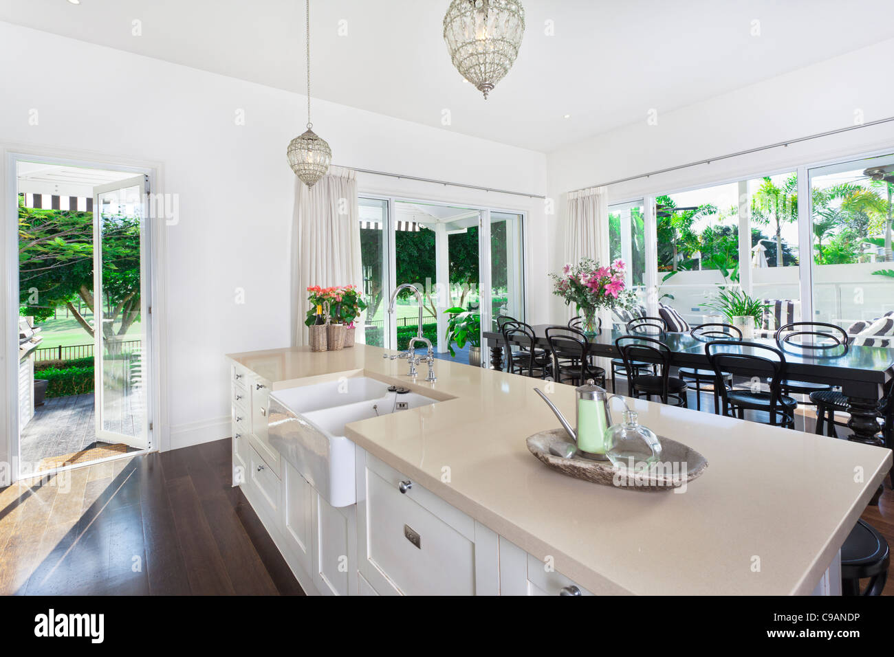 Elegante cucina aperta con un grande tavolo da pranzo che si affaccia su di un campo da golf a grana grossa e piscina Foto Stock