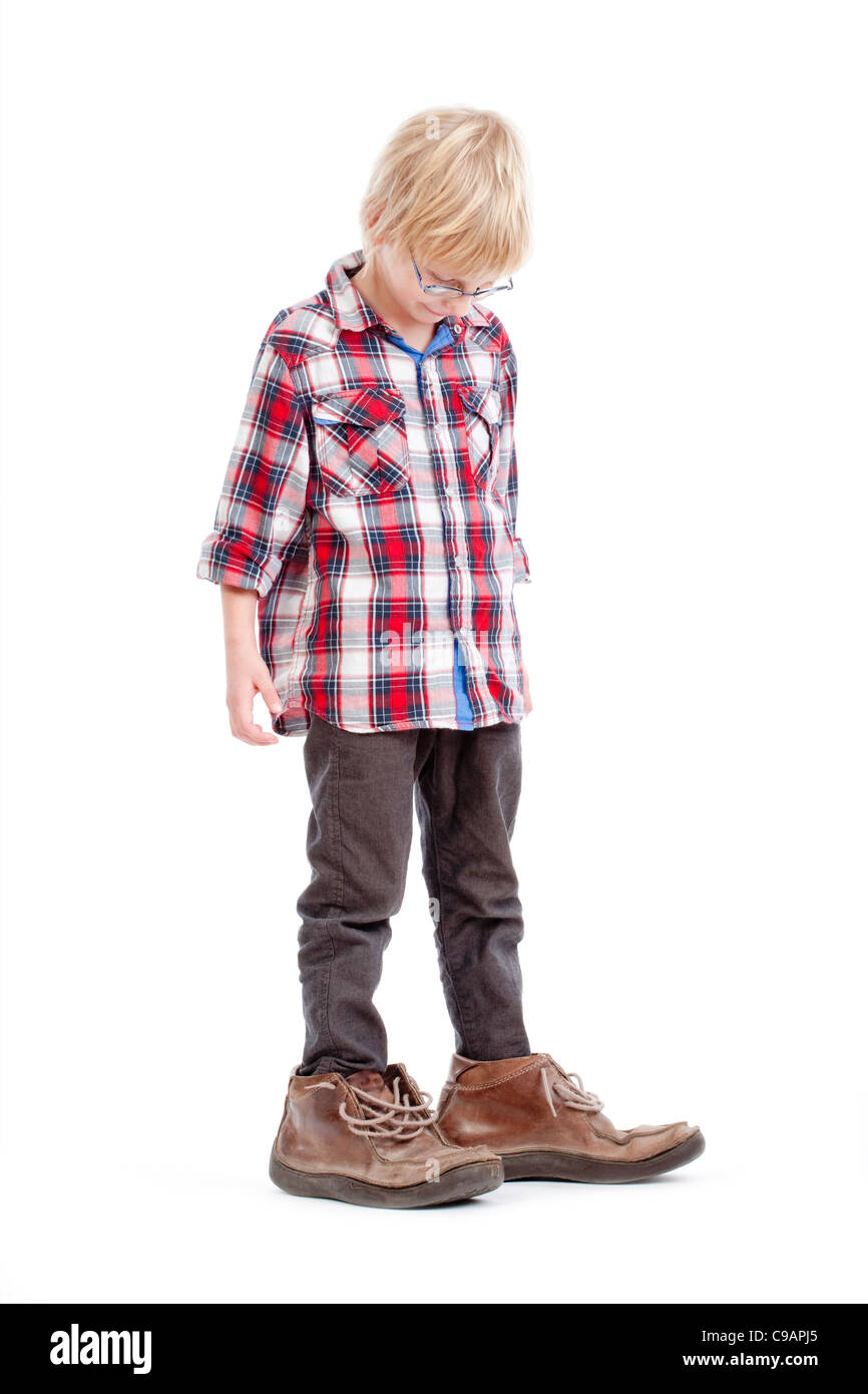 Piccolo ragazzo che indossa il suo padre's calzature - isolato su bianco Foto Stock