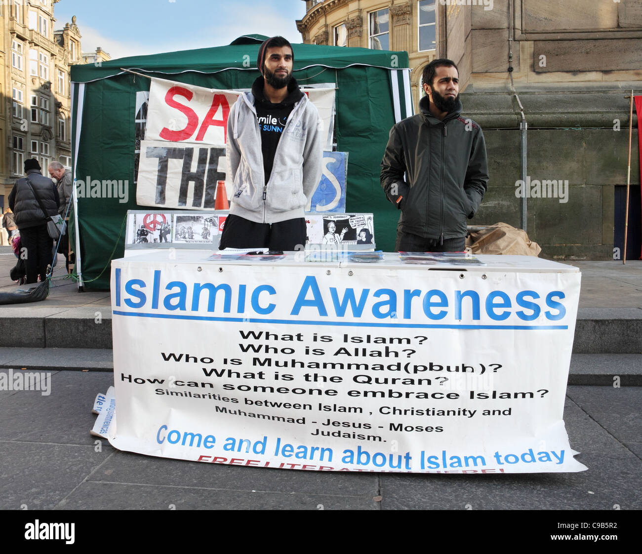 Due giovani uomini promuovendo consapevolezza islamica al piede di Grey's Monument in Newcastle, North East England, Regno Unito Foto Stock