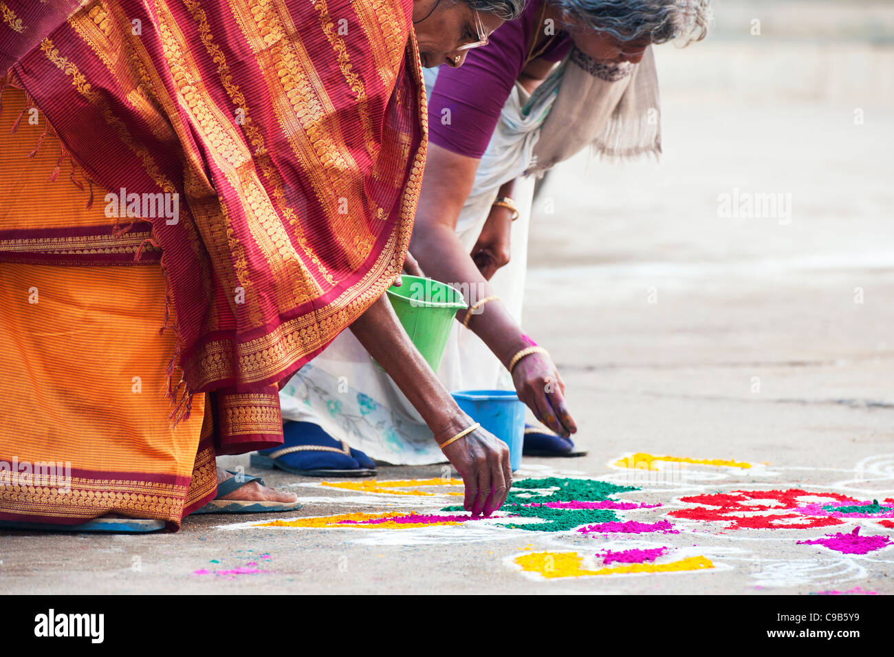 Persone anziane donne indiane facendo una Rangoli dasara design festival in un Indiano street. Puttaparthi, Andhra Pradesh, India Foto Stock