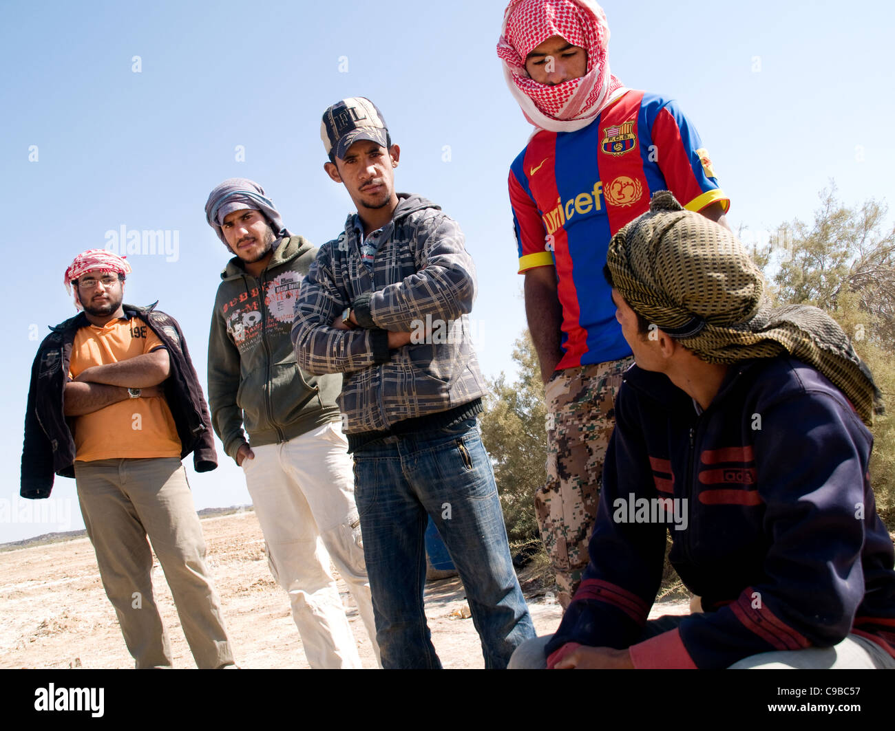 Un gruppo di giovani uomini, disoccupati Middle Eastern day-operai, in attesa di lavoro nella periferia di al Azraq oasi nel Regno Hascemita di Giordania. Foto Stock