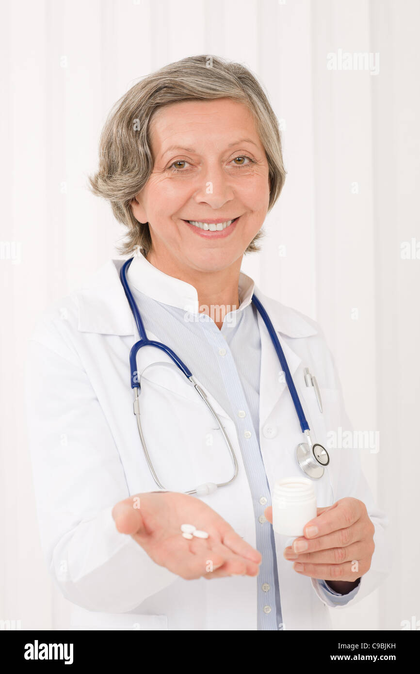 Medico senior azienda femmina pillole sorridente ritratto professionale Foto Stock