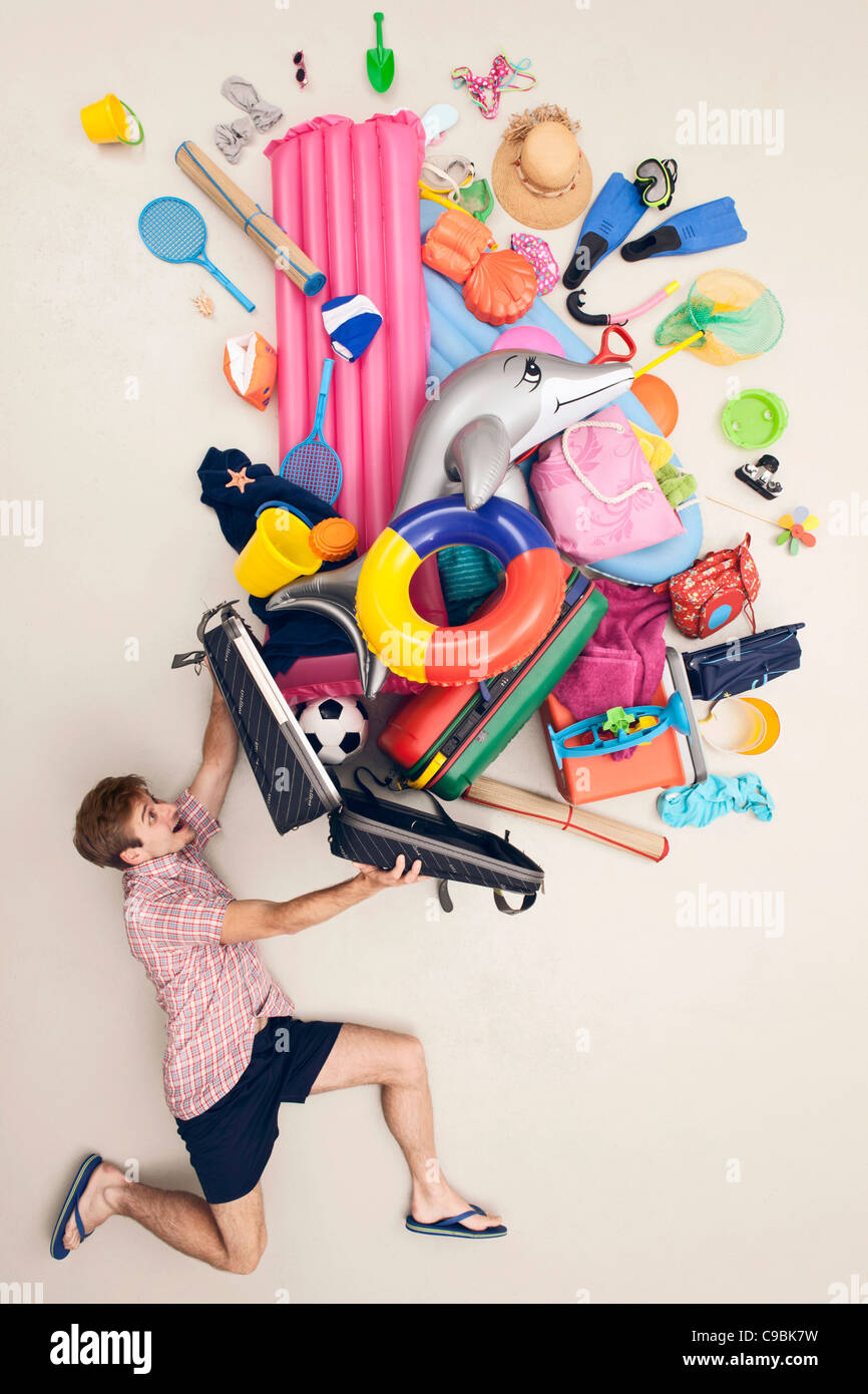 Germania, scena artificiale con uomo bagaglio di apertura piena di giocattoli da spiaggia Foto Stock