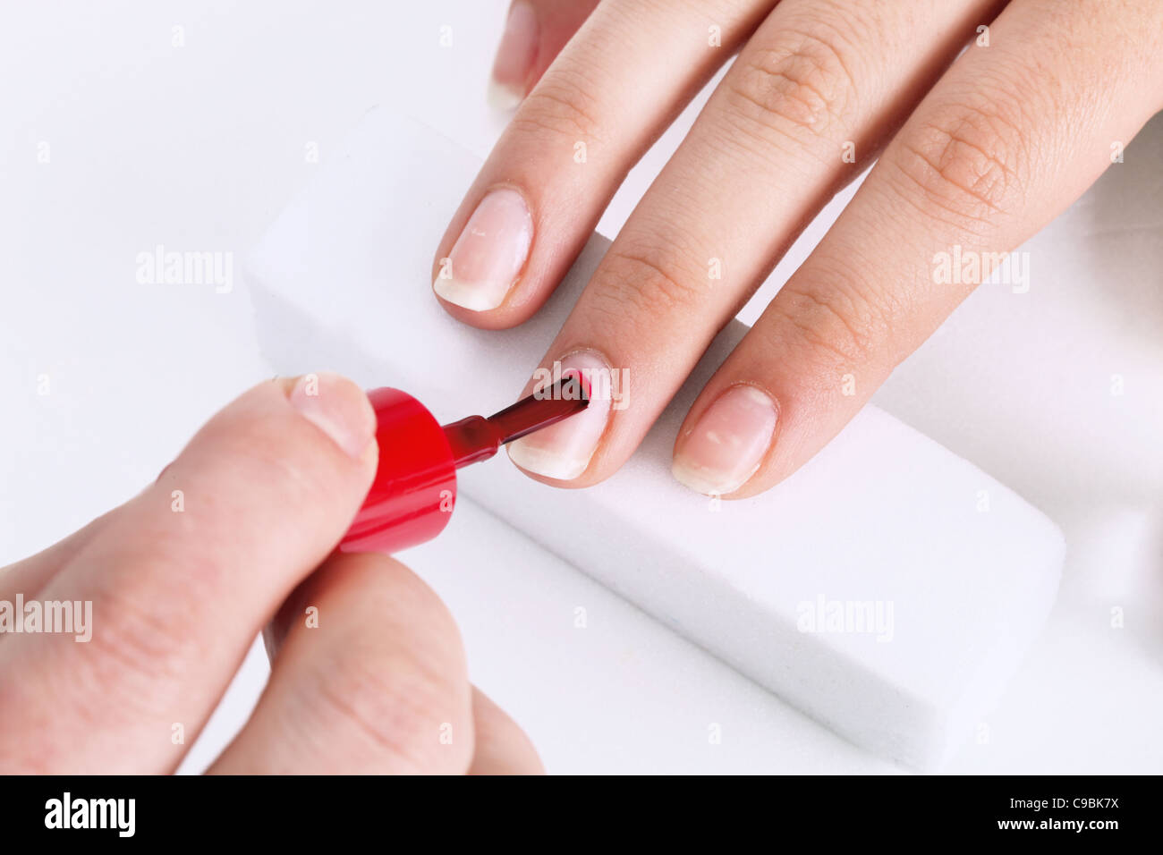 Spazzola per unghie con vernice rossa nella manicure Foto Stock