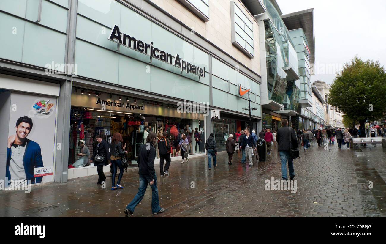 I pedoni a piedi passato American Apparel negozio vicino al centro commerciale Arndale nella zona centrale di Manchester, Inghilterra, Regno Unito Foto Stock