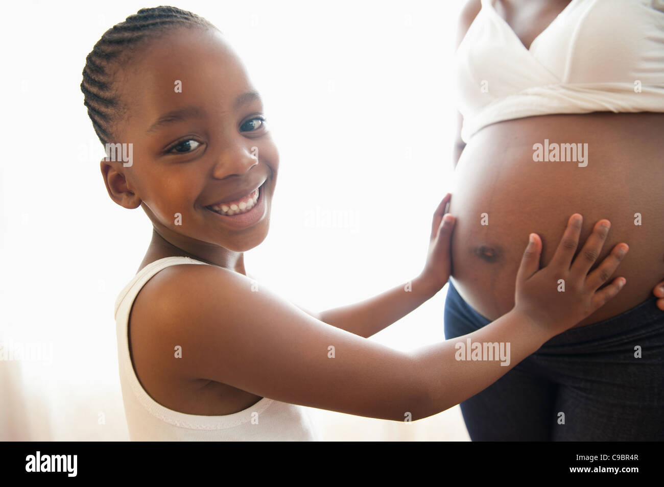 Ritratto di giovane ragazza con le mani sulla gravidanza della madre dello stomaco, Johannesburg, provincia di Gauteng, Sud Africa Foto Stock