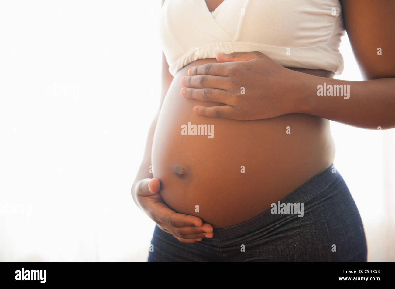 Vista ravvicinata della donna e delle sue mani cullano incinta dello stomaco, Johannesburg, provincia di Gauteng, Sud Africa Foto Stock