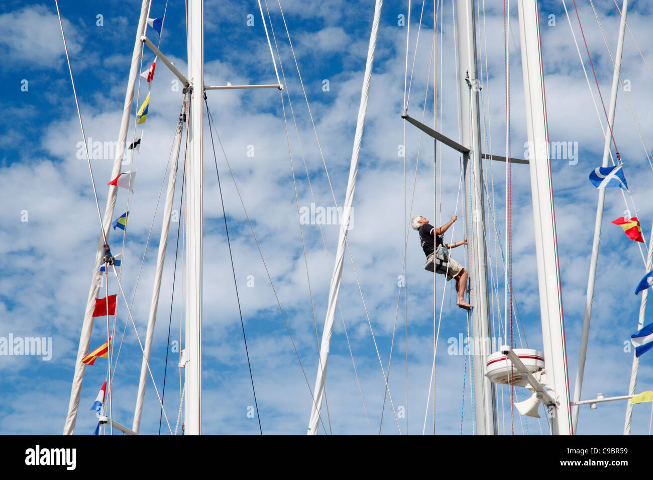 Sailor arrampicata montante di yacht per eseguire la manutenzione Foto Stock