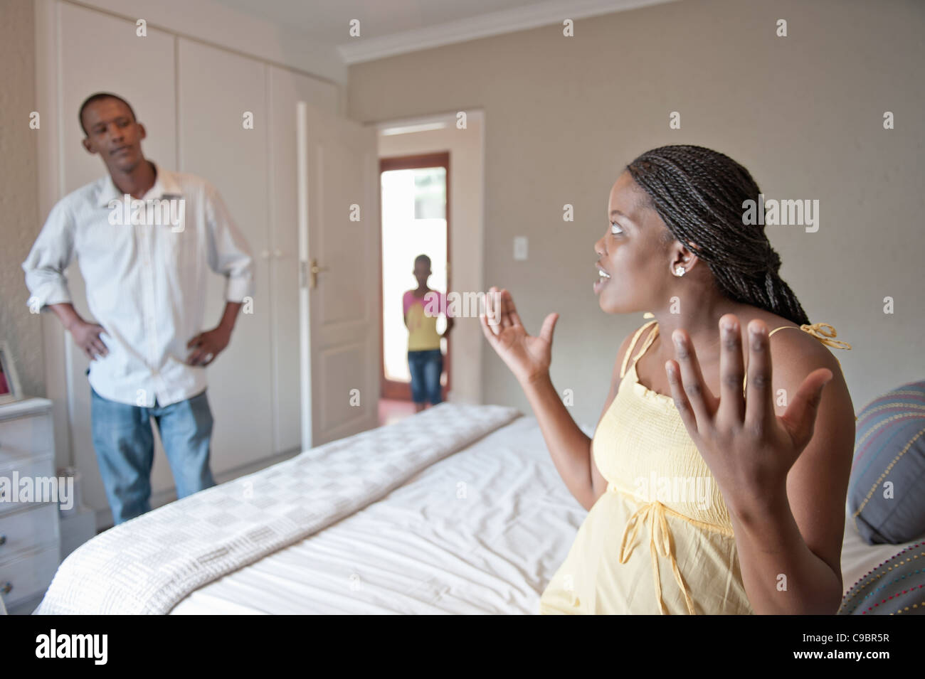 La donna incinta e il marito sostenendo mentre la figlia gli orologi della porta della camera, Johannesburg, provincia di Gauteng, Sud Africa Foto Stock