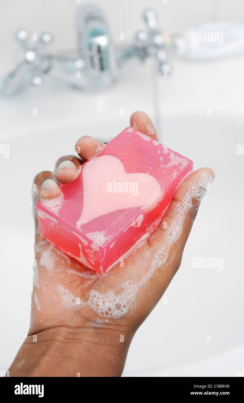 La mano della ragazza adolescente tenendo premuto barra di sapone a forma di cuore, Cape Town, Provincia del Capo Occidentale, Sud Africa Foto Stock