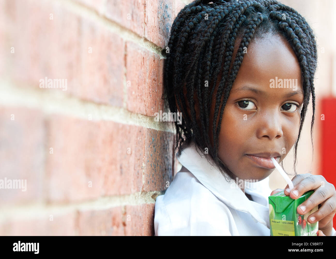 Ritratto di ragazza di bere succo attraverso la paglia al di fuori della scuola, Johannesburg, provincia di Gauteng, Sud Africa Foto Stock