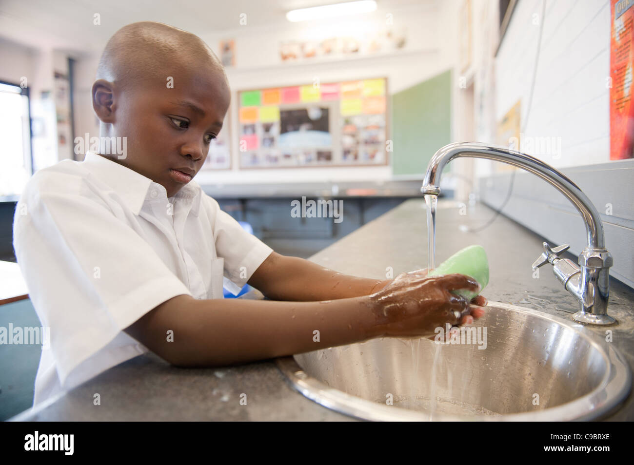 Ragazzo lavarsi le mani con sapone in aula, Johannesburg, provincia di Gauteng, Sud Africa Foto Stock