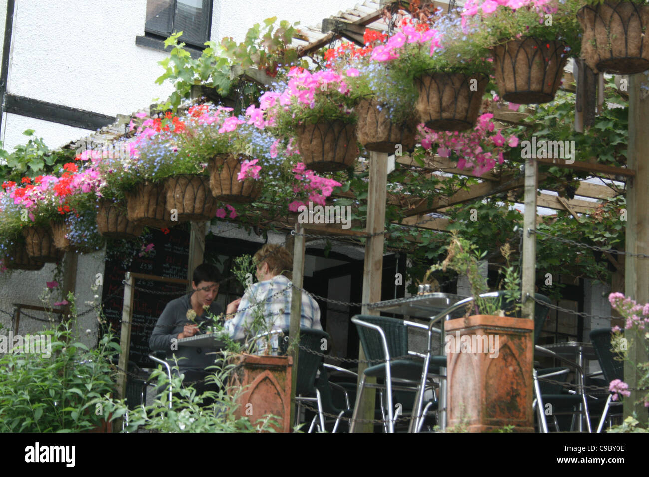 Un ristorante all'aperto con abbondanza di appendere estate cesti e camini ornamentali. Foto Stock