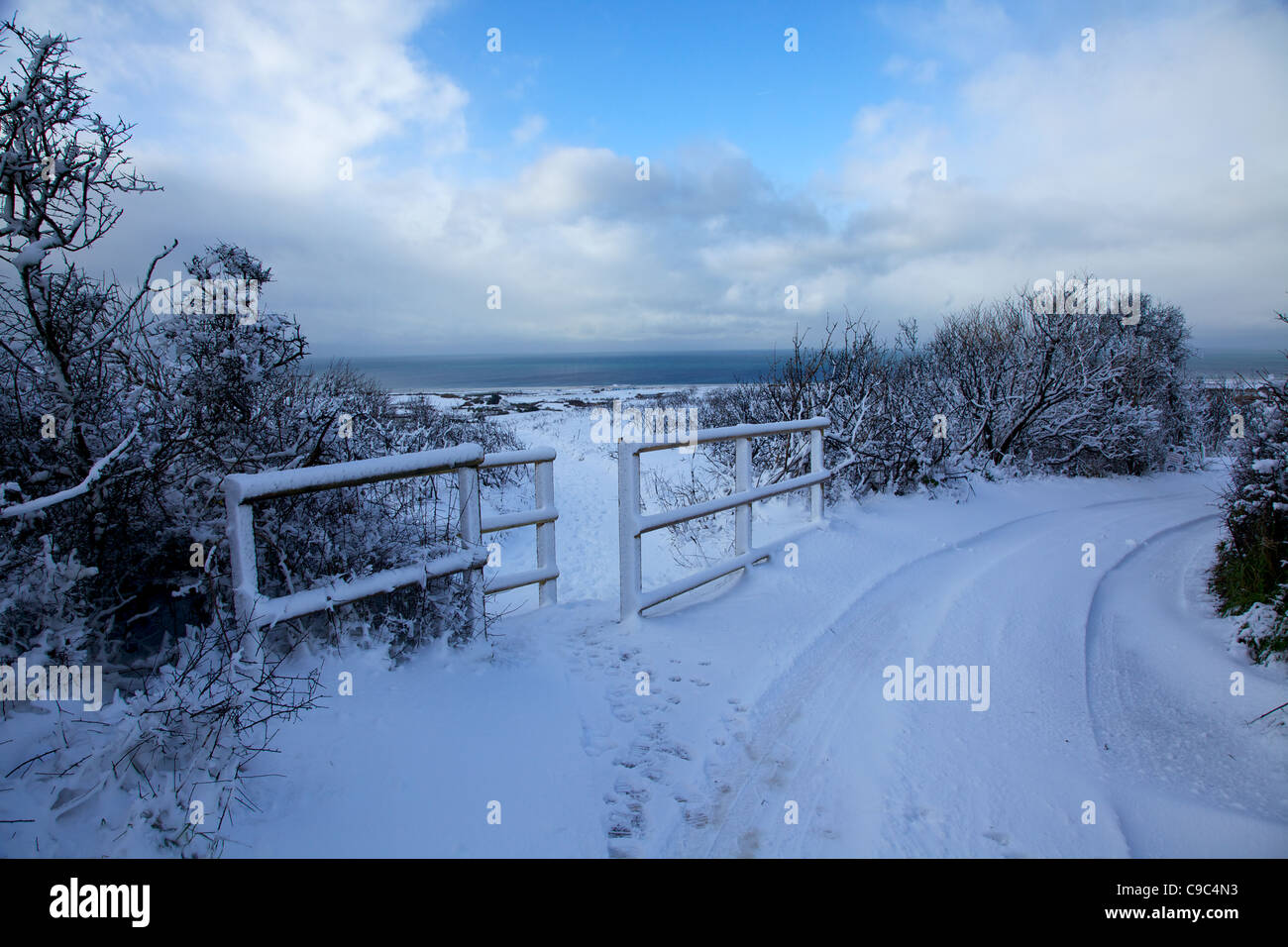 In inverno la neve paesaggio della carreggiata e la recinzione con blue sky rottura attraverso Foto Stock