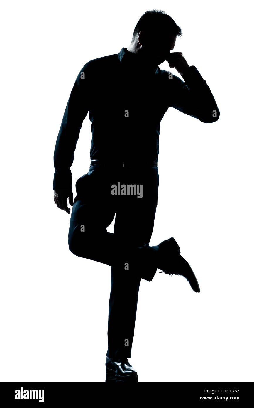 Un uomo caucasico guardando le sue scarpe odore sgradevole a piena lunghezza silhouette in studio isolato sfondo bianco Foto Stock