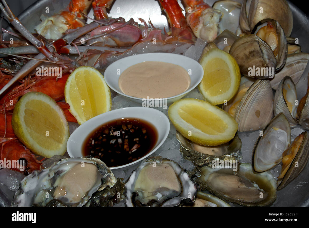 Piatto di frutti di mare ostriche di greggio le vongole cotte al vapore materie gamberi crab gambe salse di immersione la metà dei limoni Foto Stock