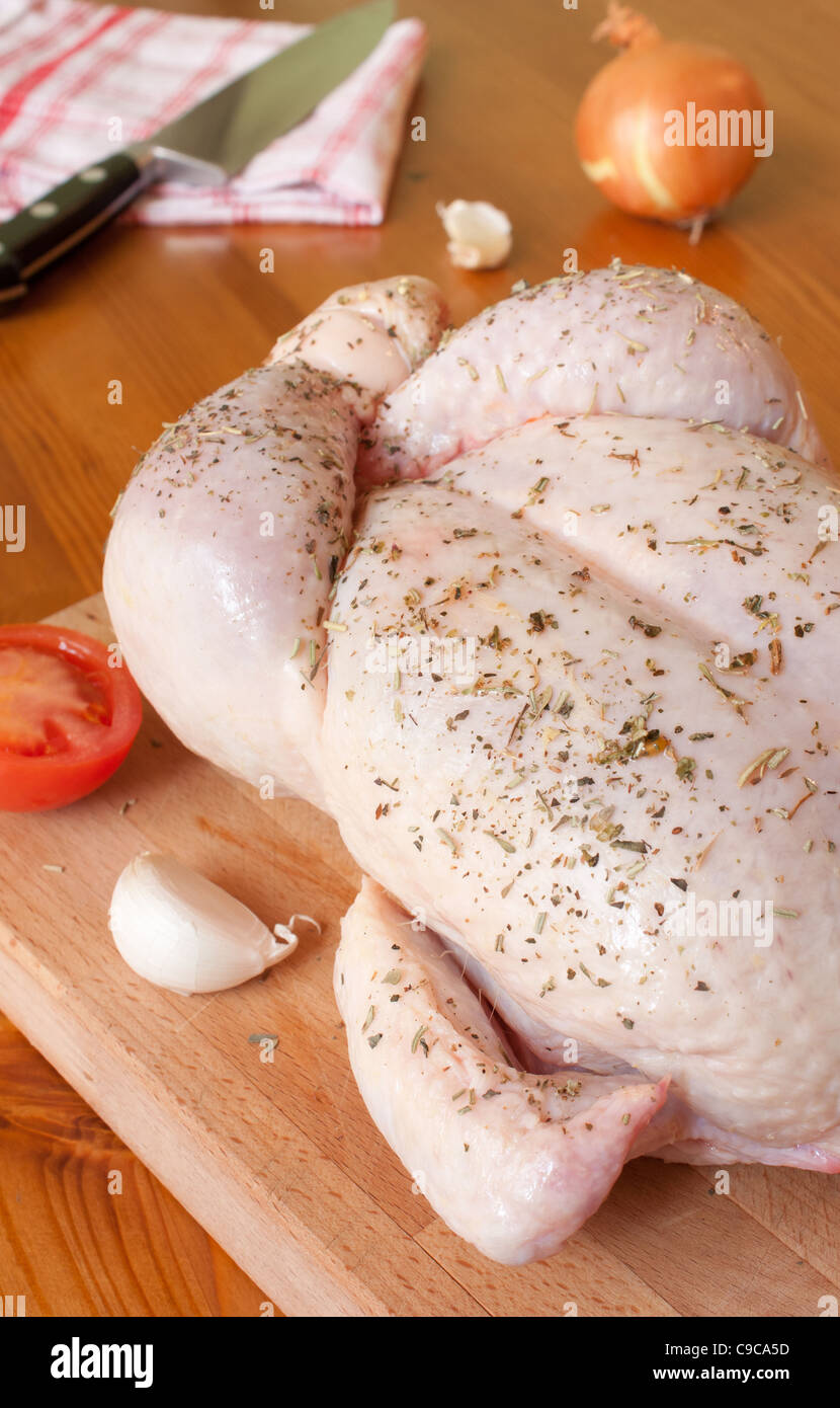 Preparazione di un pollo provenzale, con erbe aromatiche, aglio, cipolle e pomodori Foto Stock