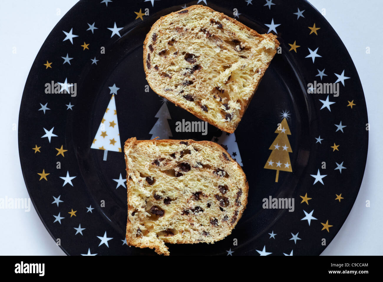 Gocce di cioccolato il panettone tagliato a metà e posto sul Natale decorativo piastra e impostare contro uno sfondo bianco Foto Stock