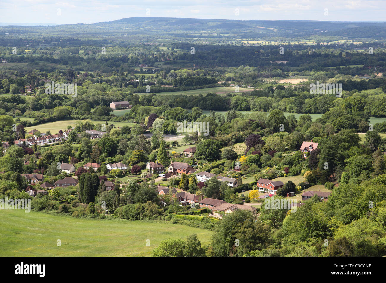 Case nel bosco vicino a Reigate, Surrey, Regno Unito viste dai North Downs che guardano attraverso il Weald verso il Sussex. Parte della Green Belt di Londra. Foto Stock