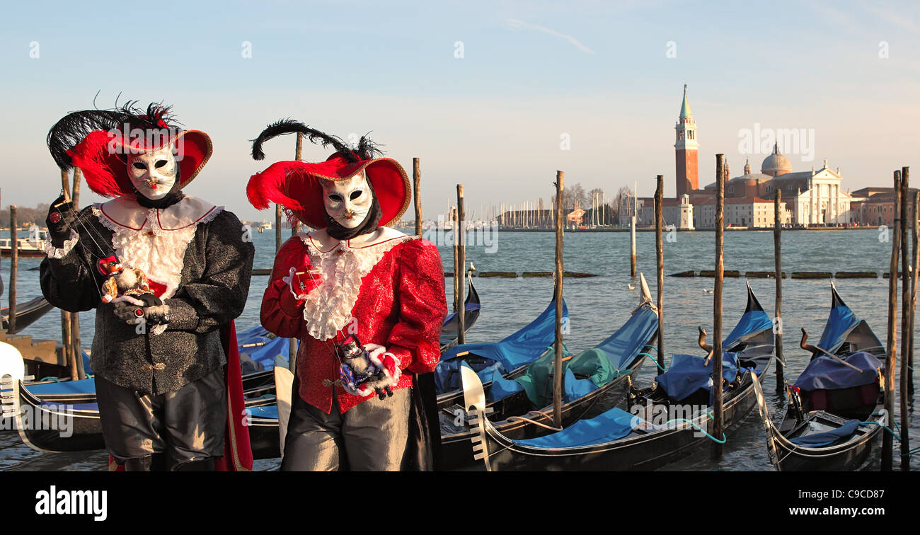 Due partecipanti nei tradizionali costumi da carnevale veneziano contro il Canal Grande e la chiesa di San Giorgio Maggiore a Venezia, Italia. Foto Stock
