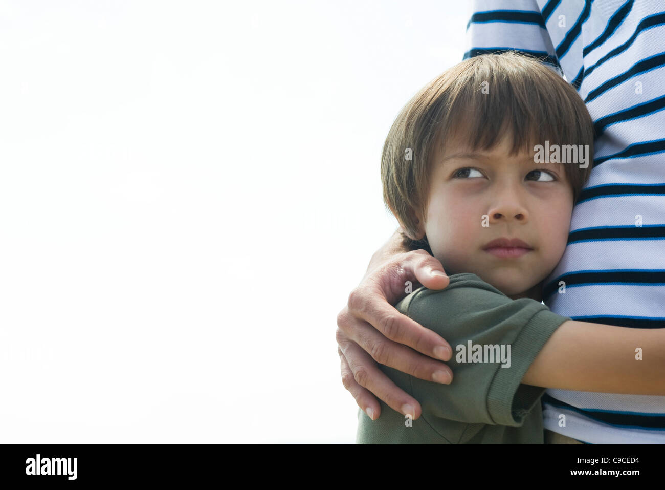 Ragazzo che abbraccia il suo padre, guardando lontano nel pensiero Foto Stock