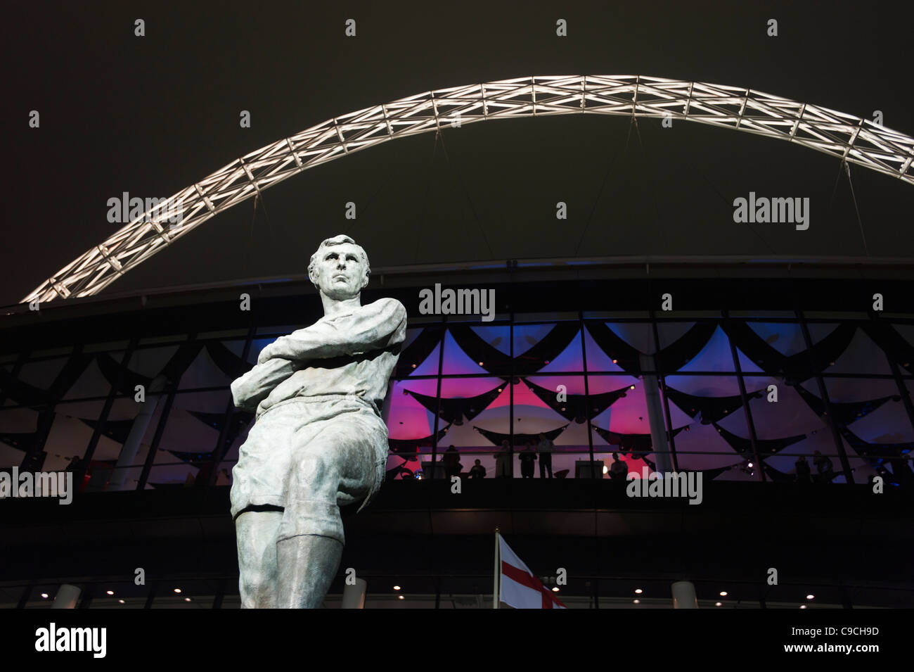 Statua di Bobby Moore al di fuori del ri-sviluppato lo Stadio di Wembley a Londra, illuminata di notte. Foto Stock