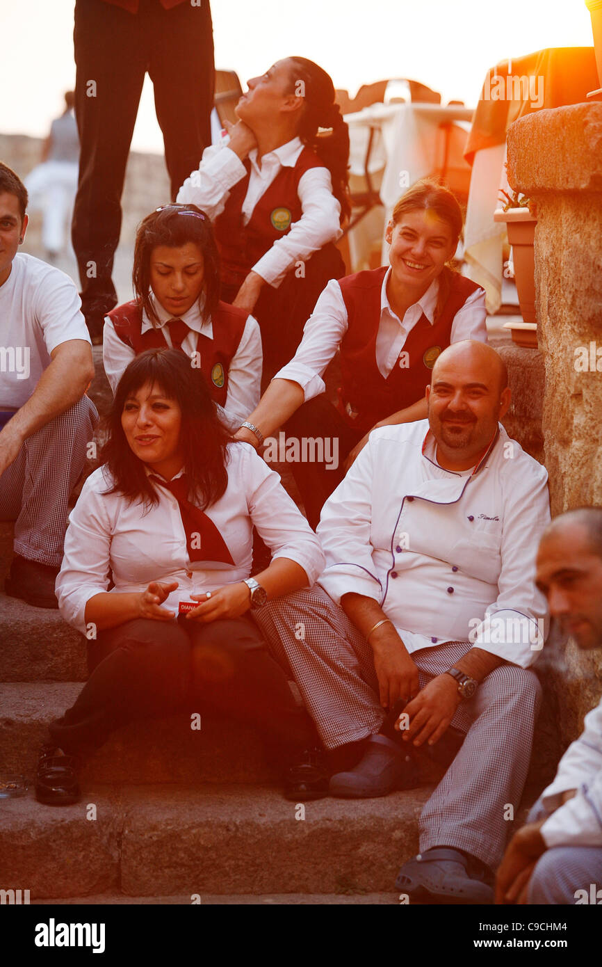 Il personale del ristorante nella città vecchia avente una pausa, Alghero, Sardegna, Italia. Foto Stock