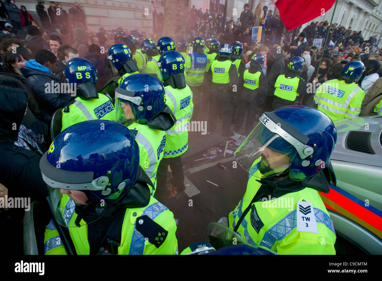 La polizia di tumulto ruota dentata costituente una barriera su Whitehall, bagnata in rosso il fumo proveniente da una svasatura, giorno X manifestazione studentesca, 24 novembre 2010, Londra, Inghilterra Foto Stock