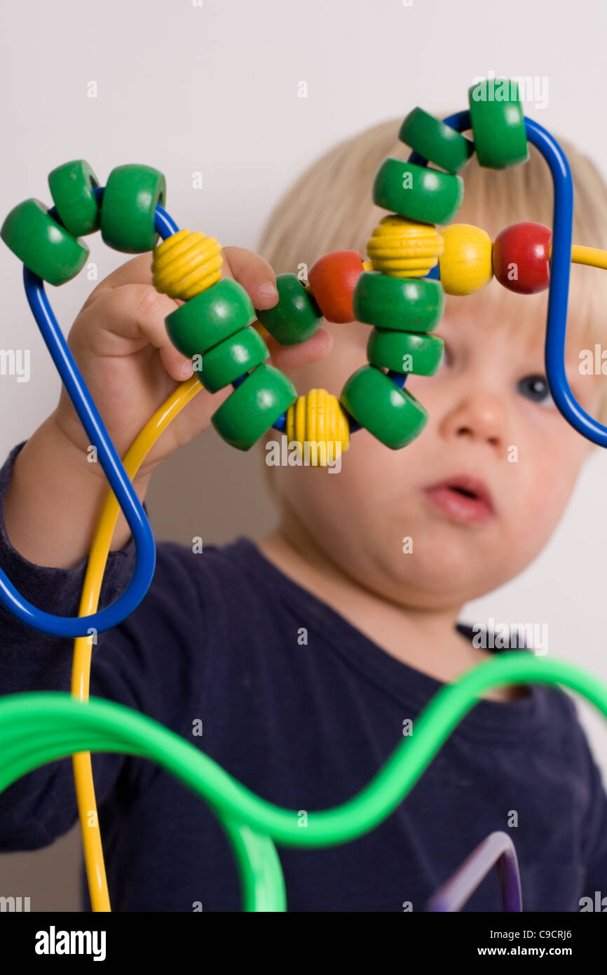 Ragazzo giovane gioca con le perline colorate su una tabella di riproduzione Foto Stock