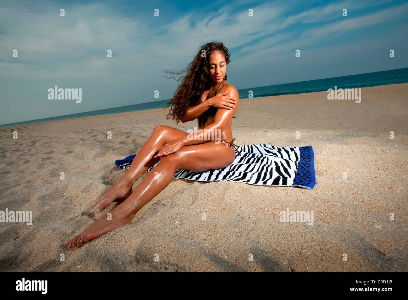 Stati Uniti d'America, Florida, Donna in bikini seduto sulla spiaggia e di  applicare una lozione Foto stock - Alamy