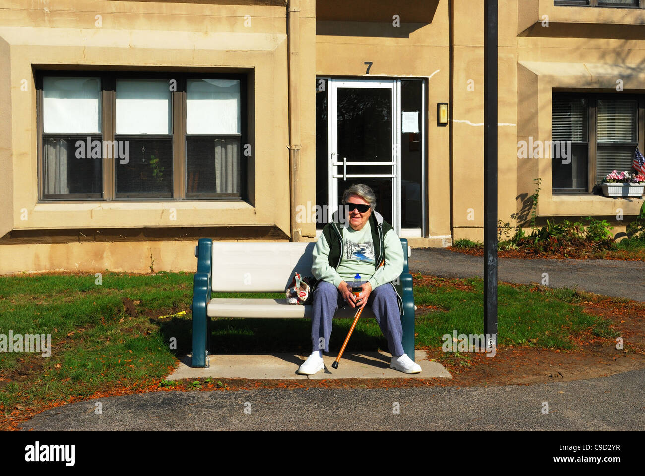 Senior donna si siede su un banco di lavoro nella parte anteriore del suo appartamento. Foto Stock