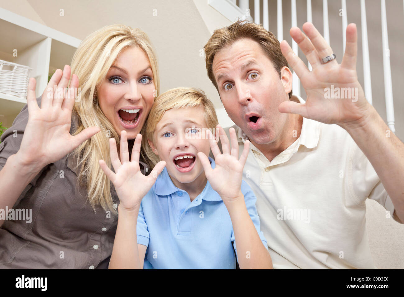 Un attraente felice, ridendo famiglia della madre, padre e figlio seduto su un divano a casa avendo divertimento Foto Stock