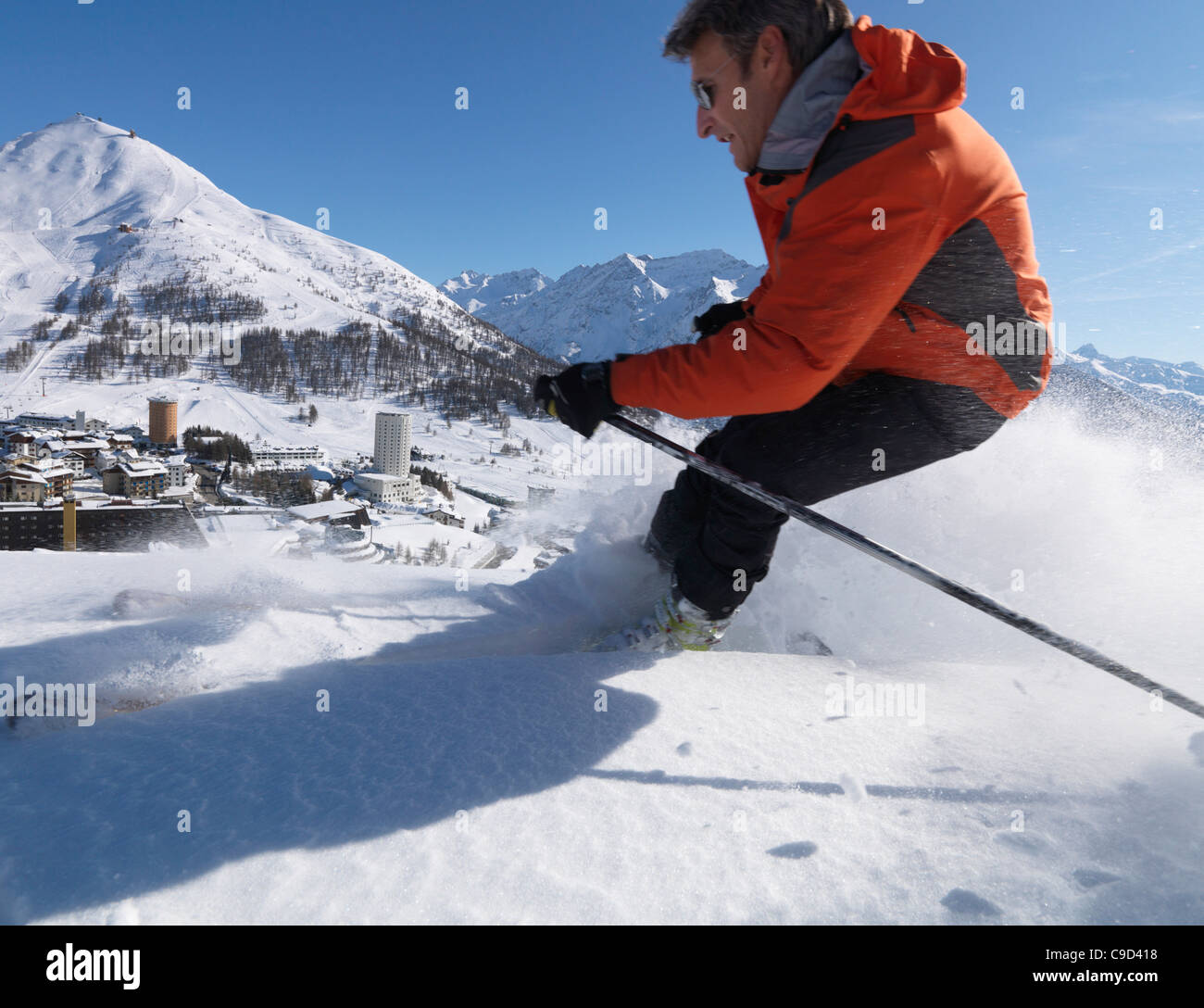 L'Italia, Piemonte, Sestriere village e ski resort (sito di giochi olimpici invernali), con sciatore in primo piano Foto Stock